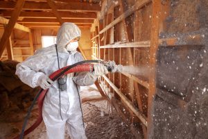 attic insulation company employee applying spray foam insulation